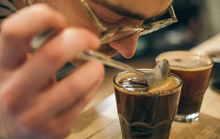 Man carefully smelling a glass of coffee