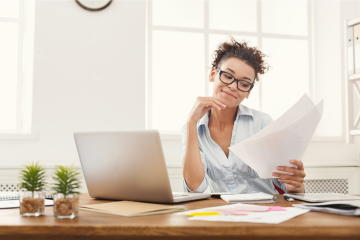 Photo of woman at computer reviewing a paper